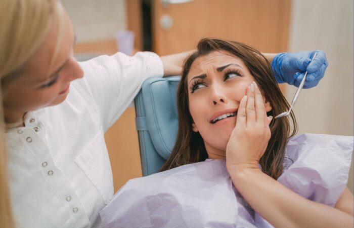 Gece saatlerinde diş ağrısı yaşayan bir bireyin çene ve yüz bölgesini tutarken gösteren görsel.