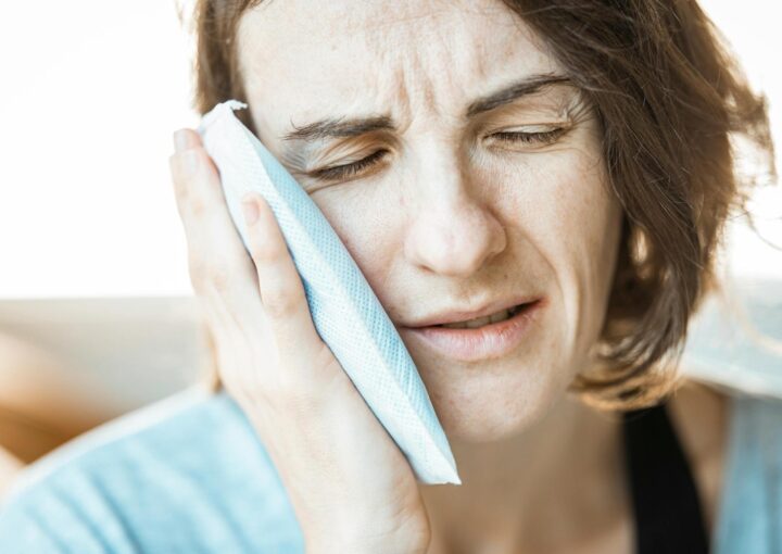 Acil diş ağrısı yaşayan bir bireyin yüz ve çene bölgesini tutarken gösteren bilgilendirici görsel.
