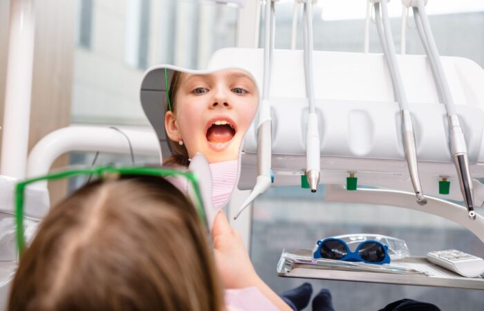 İlk diş hekimi kontrolüne gelen küçük çocuğun ağız ve diş muayenesini gösteren klinik görsel.