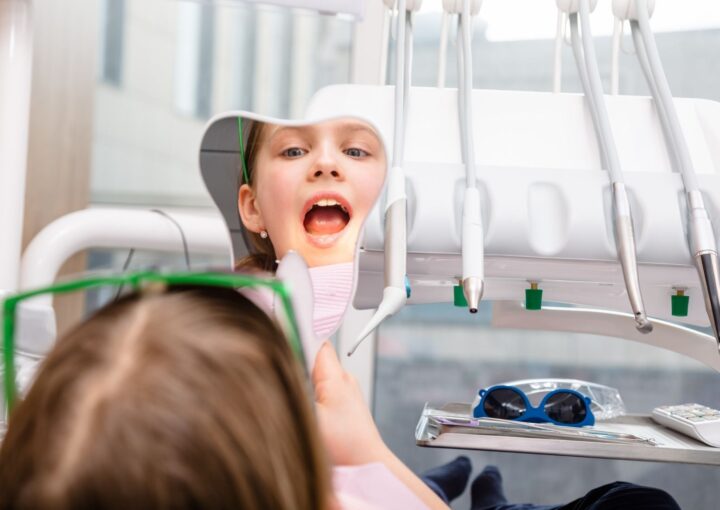İlk diş hekimi kontrolüne gelen küçük çocuğun ağız ve diş muayenesini gösteren klinik görsel.